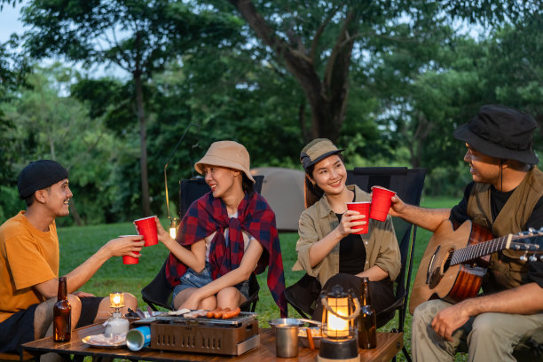 干杯!一群亚洲人朋友在大自然中露营，用软饮料和啤酒举杯祝酒。户外聚会在露营地自然森林背景在假日周末假期图片下载