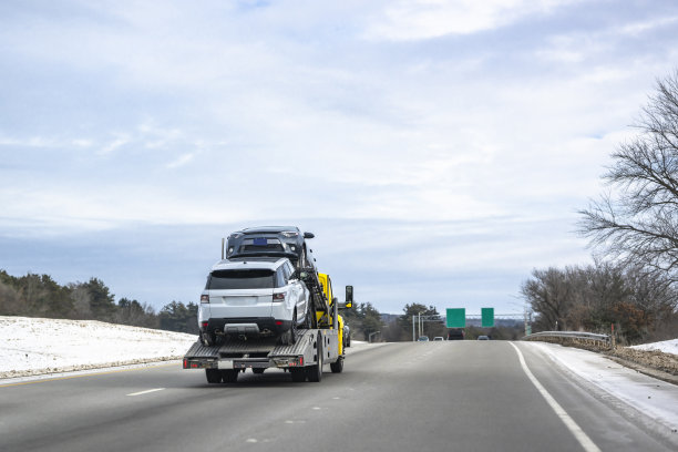 黄色中值日驾驶室钻机拖车半挂车运输汽车的小型模块化半挂车行驶在冬季高速公路上与雪在侧山上图片下载