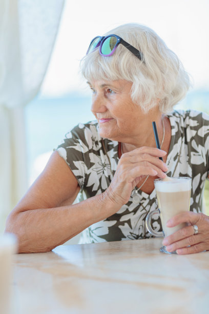 迷人的老女人坐在夏日的户外咖啡馆里图片下载