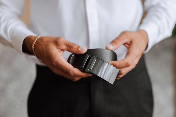 时尚的男士皮革黑色腰带在男人的手中，手的特写照片图片下载