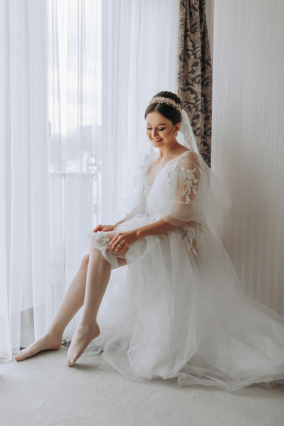 一位穿着透明长袍、头戴王冠、留着婚礼发型的美丽少女，正在皇家室内酒店准备婚礼。长面纱，自然光，人像照片图片下载