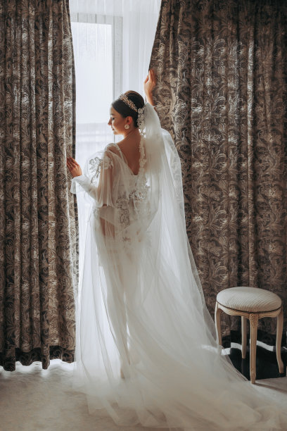 一位穿着透明长袍、头戴王冠、留着婚礼发型的美丽少女，正在皇家室内酒店准备婚礼。长面纱，自然光，人像照片图片下载