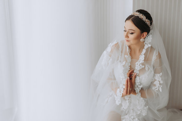 一位穿着透明长袍、头戴王冠、留着婚礼发型的美丽少女，正在皇家室内酒店准备婚礼。长面纱，自然光，人像照片图片下载