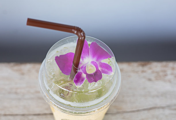 饮料装在塑料玻璃杯里，照片上的角落里装饰着鲜花。图片下载
