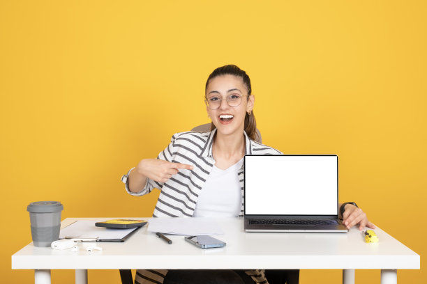 女商人坐在办公桌前，用笔记本电脑指着空屏幕模拟。图片下载