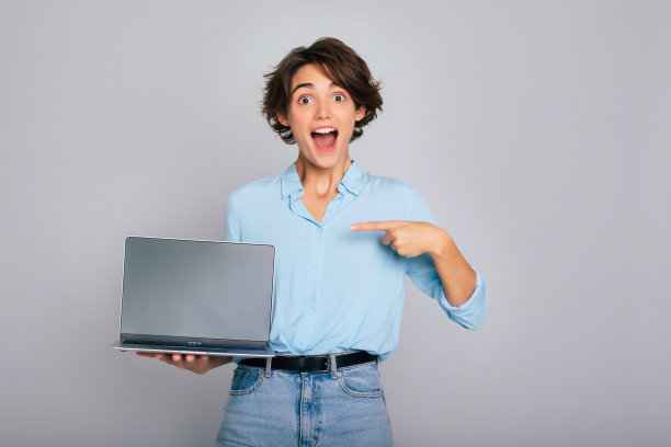 一个穿着漂亮休闲装的震惊而兴奋的女性的特写照片显示，她手里拿着笔记本电脑，屏幕空白，嘴巴张开。为你的应用和公司广告提供复制空间图片下载