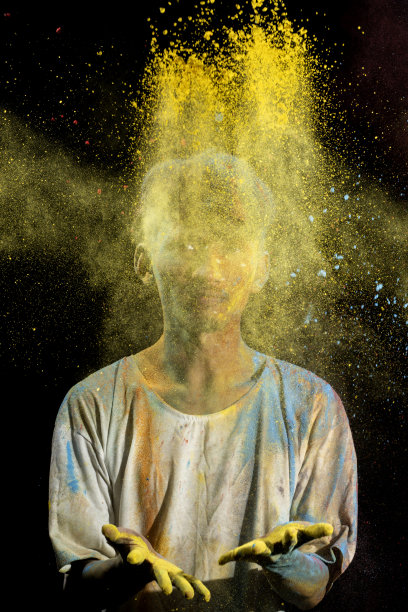 一名亚洲男子身上洒满了五彩缤纷的胡里节粉末，在黑色的背景上玩得很开心。图片下载