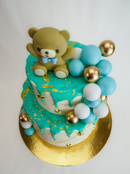 蛋糕上面有一只泰迪熊，还有金色和蓝色的装饰图片下载