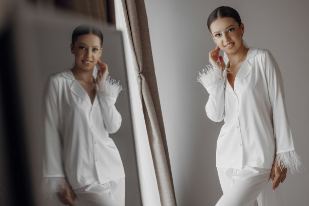 清晨穿着白色睡衣的年轻美丽的新娘。新娘在酒店的早晨。长长的时尚面纱。镜子照片图片下载