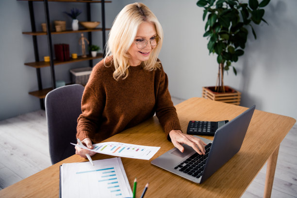 统计分析的成年专家女性照片在办公室里用笔记本电脑计算年利润图片下载