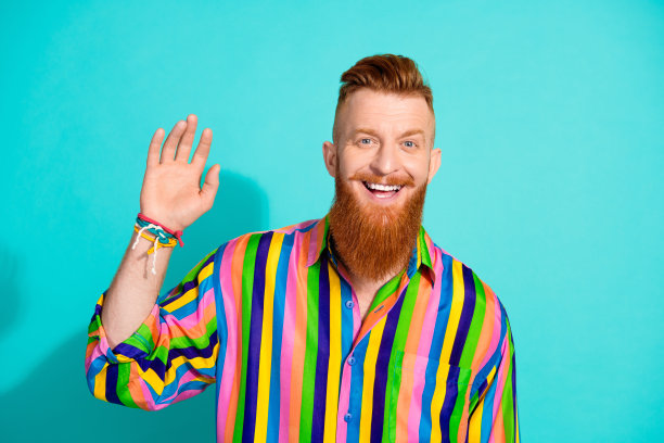 照片中，积极开朗的男子穿着鲜艳的衣服，举手打招呼，标志孤立在青色背景上图片下载