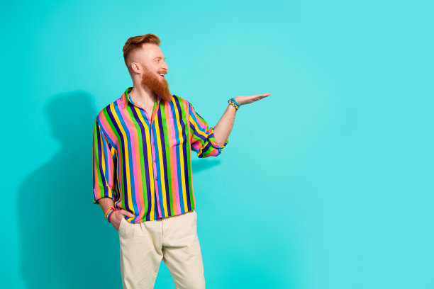 照片中的年轻英俊的红发男子在条纹衬衫拿着copyspace迷你版玩具的女朋友孤立的青色背景图片下载