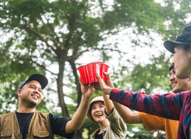 干杯!一群亚洲人朋友在大自然中露营，用软饮料和啤酒举杯祝酒。户外聚会在露营地自然森林背景在假日周末假期图片下载