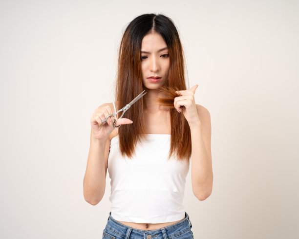 年轻的亚洲女性有头发问题，头发薄，受损，干燥，容易脱落，不健康，必须剪掉。站在孤立的白色背景上图片下载