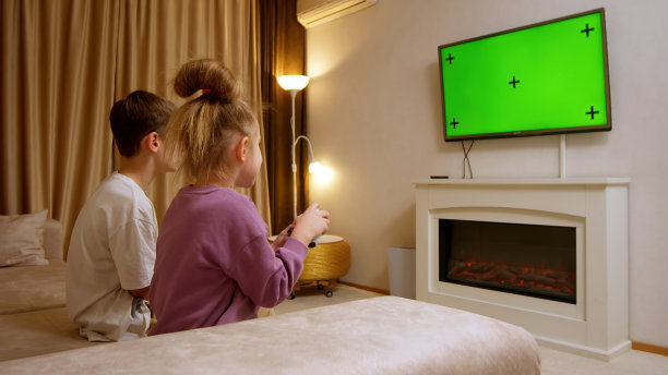 孩子们在室内享受着对着绿色电视屏幕背景玩游戏。游戏机，电子游戏，科技，娱乐。图片下载