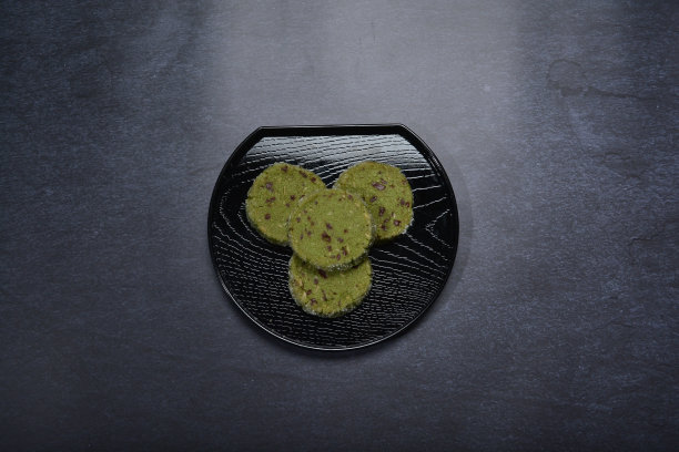 烘焙豪华抹茶绿茶与混合坚果巧克力片糖钻石貂皮圆饼干和黑盘金叉刀暗背景糕点甜点清真无麸质素食食品菜单图片下载