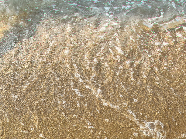 一个人拿着冲浪板站在沙滩上的照片。图片下载