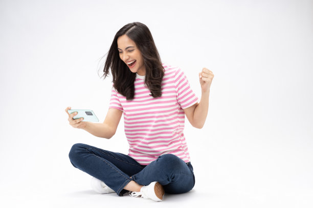 漂亮的年轻女孩的全尺寸照片坐在地板上拿着电话电子商务穿着时髦的服装孤立在白色背景的股票照片图片下载