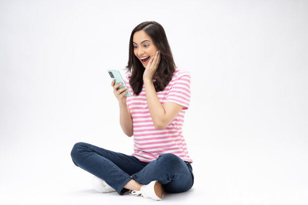漂亮的年轻女孩的全尺寸照片坐在地板上拿着电话电子商务穿着时髦的服装孤立在白色背景的股票照片图片下载