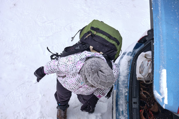 一家人滑雪自驾游，女人从汽车行李箱里卸下行李图片下载