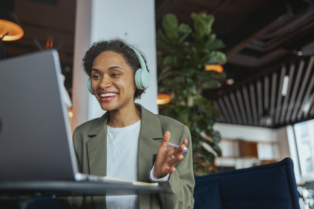 一位戴着耳机的女士坐在笔记本电脑前图片下载