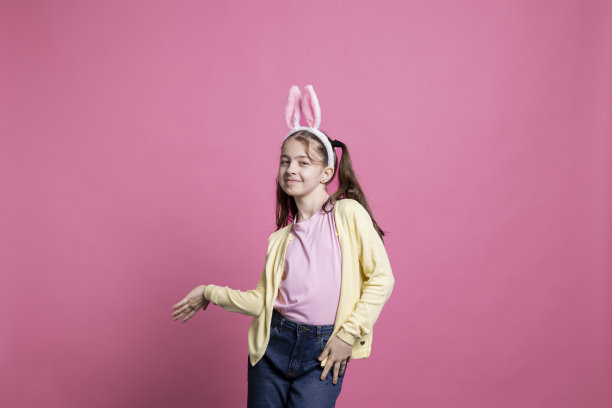 欢快的小孩扎着小辫，戴着兔耳朵在镜头前跳舞图片下载