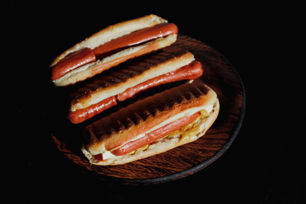 三个美味的，刚准备好的热狗陈列在一个黑色的木摊上。概念野餐或烧烤与家人和朋友。高质量照片图片下载