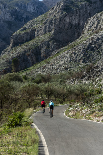 两个骑自行车的人在科斯塔布兰卡山路，阿利坎特-股票照片图片下载