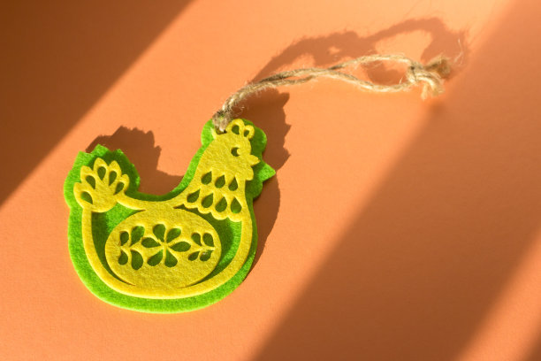 复活节贺卡快乐。毛毡母鸡在桃色毛绒绒的背景。阳光下的小鸡玩具。欢快的复活节概念。四月节日装饰。喜庆的春天壁纸。图片下载