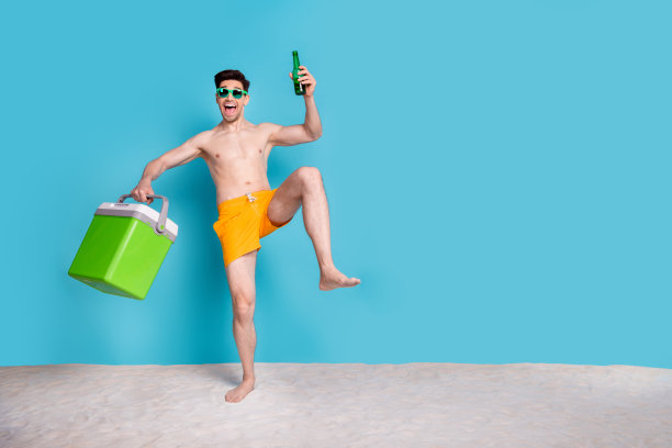欢快时髦的赤膊男子走在海滩享受啤酒空空间孤立的蓝色背景的全长照片图片下载