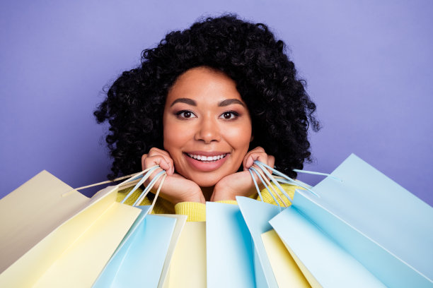 照片肖像迷人的年轻女子触摸脸颊购物袋穿着时尚的黄色衣服孤立的紫色背景图片下载