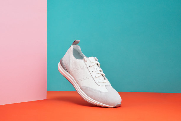 时尚白色运动鞋与皮革口音在柔和的渐变背景。运动鞋，街头穿在空中。产品照片或悬浮概念。图片下载