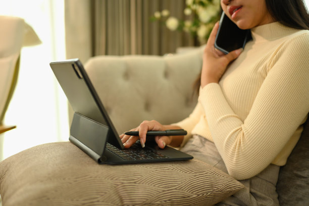 剪短的照片，年轻女子在家里打电话和用数码平板电脑工作图片下载