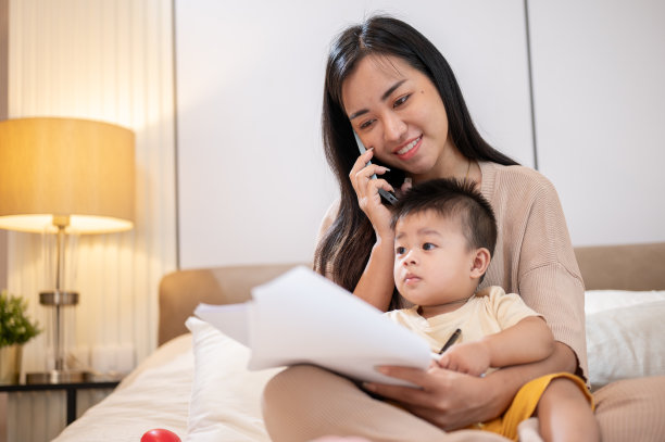 一位母亲一边打电话一边处理文件，一边照顾她的小儿子。图片下载