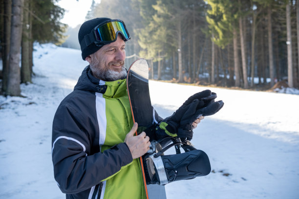 一个开朗的老人，头发花白，留着胡子，穿着绿色、黑色、灰色和白色的运动滑雪服。图片下载