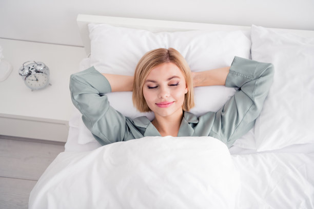 可爱的金发女郎躺在床上的照片肖像手在头后面睡觉穿时髦的灰色睡衣舒适的卧室白天图片下载