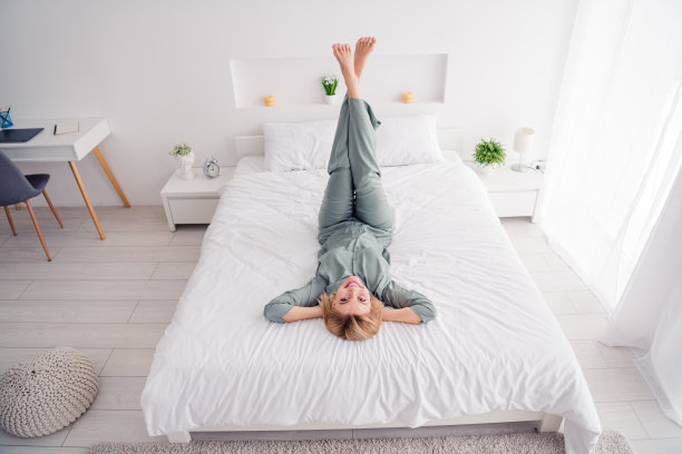 金发的全身照片年轻快乐的女孩穿着灰色的睡衣睡午觉无忧无虑的白日梦在床上抬头在家里室内图片下载
