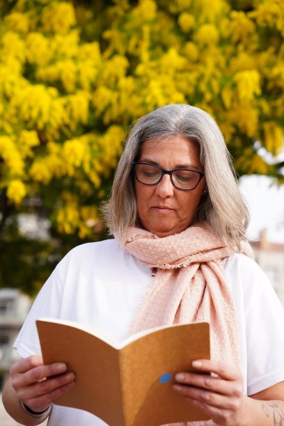 白发女人在公园里看书。图片下载