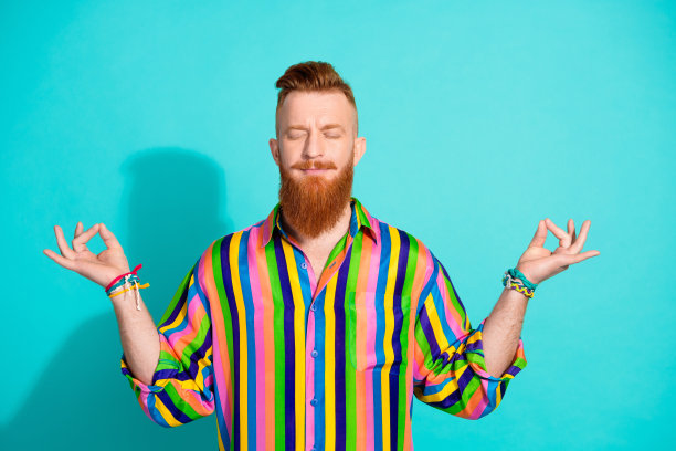 照片中，梦幻般的男人穿着时髦的衣服，闭着眼睛瑜伽冥想，孤立在青色的背景下图片下载