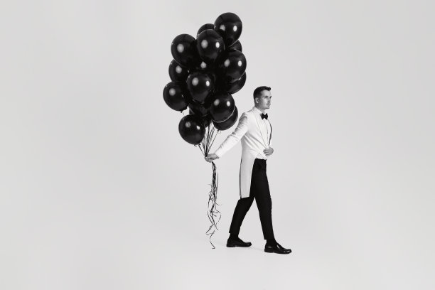 白人男子，白色西装，无尾礼服，带着黑色气球图片下载