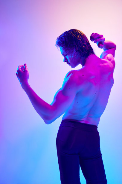 照片中赤裸上身的男子在紫色霓虹灯下的背影，背景渐变为蓝粉色。后面的观点。图片下载