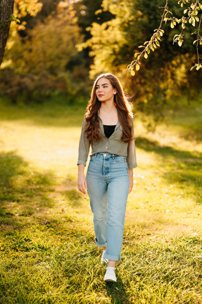 一个金发女郎在阳光明媚的一天走在公园草地上的全身照片。图片下载