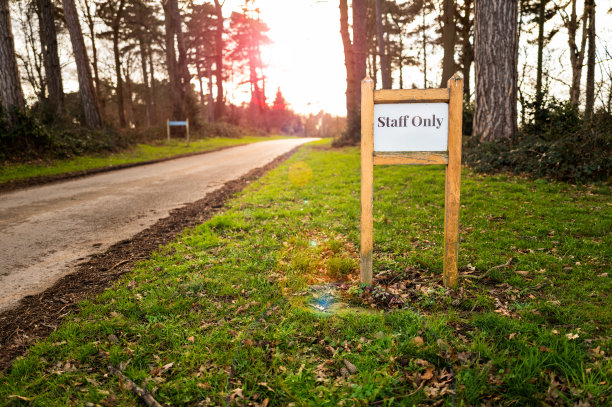在一条通往英格兰乡村中心的豪华酒店的荒凉的乡村道路上，一个员工专用标志的浅焦点。图片下载