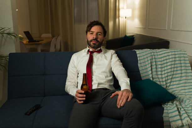 下班后喝着啤酒躺在沙发上的疲惫男人图片下载