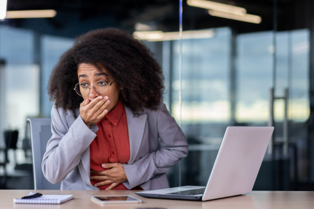 生病的非裔美国女性，有严重的恶心发作，用手掌捂住嘴以防止呕吐。不健康的女士在工作场所抱着肚子时胃痛和抽筋图片下载