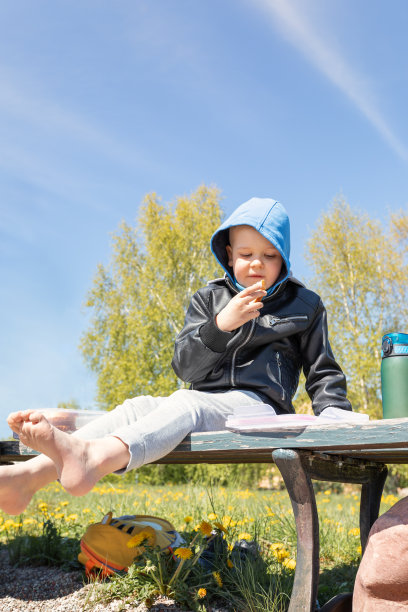 一个孩子在大自然的长凳上吃三明治。低角度照片。图片下载