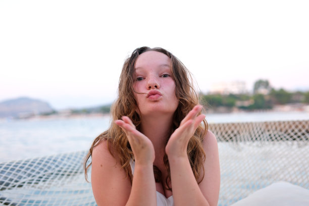 只为你。照片漂亮迷人的卷发女士送飞吻打开手掌调情男朋友诱人的嘴唇穿白色休闲背心孤立的亮粉色背景图片下载