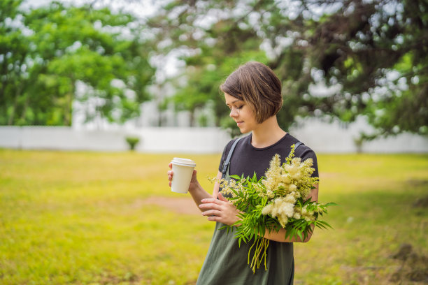 年轻女子手里拿着一个装有咖啡或茶的纸杯图片下载