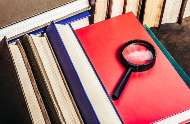 用放大镜看桌子上的古书照片。图片下载
