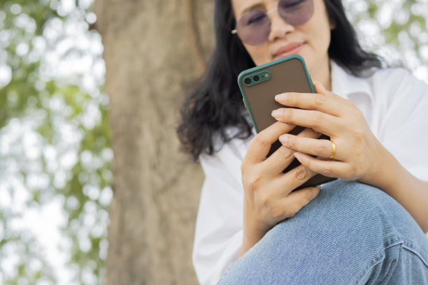 照片中，成熟的漂亮女人戴着眼镜，用智能手机在社交网络上打字图片下载
